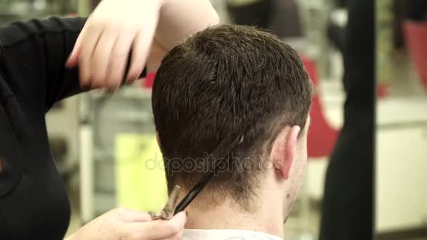Saç stilisti saçını kestirmek için genç bir adam yapıyor — Stok video