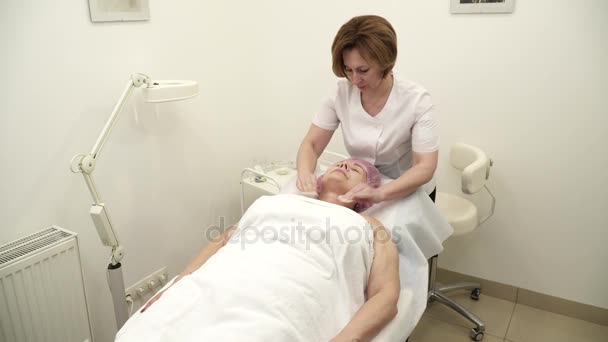 Esteticista está haciendo un procedimiento de lifting facial para una mujer anciana — Vídeo de stock