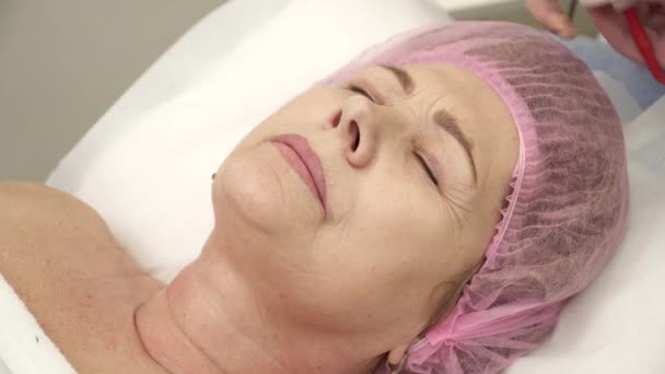 Esteticista está haciendo un procedimiento de lifting facial para una mujer mayor en el salón — Vídeos de Stock