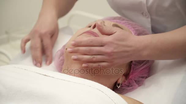 Kosmetolog är att göra ett ansikte lyft förfarande för en äldre kvinna i salong närbild — Stockvideo