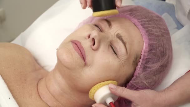 Косметик делает процедуру подтяжки лица для пожилой женщины — стоковое видео