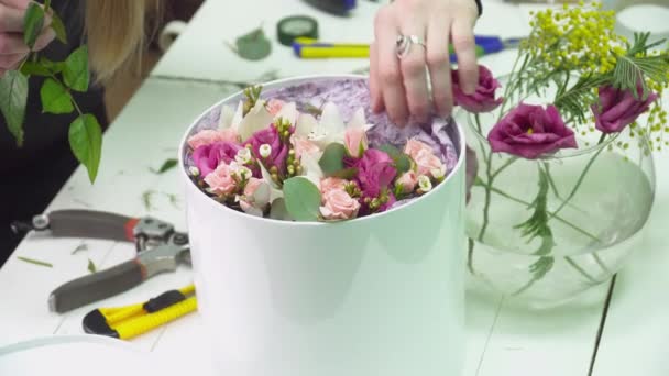 Флорист заповнює коробку трояндами у квітковому магазині — стокове відео
