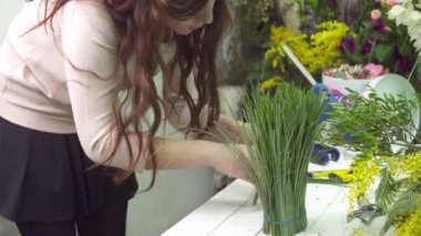 Çiçekçi bir buket masaya yapıyor