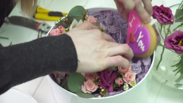 Květinářství přidává perník ve tvaru srdce do kytice — Stock video