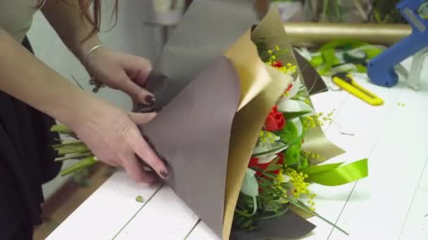 Флорист заворачивает букет в оберточную бумагу крупным планом — стоковое видео