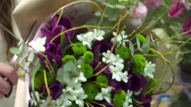 Florista está enrolando o buquê com tulipas em suas mãos — Vídeo de Stock