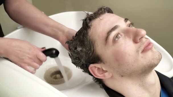 Hairdresser is washing young mans hair — Stock Video