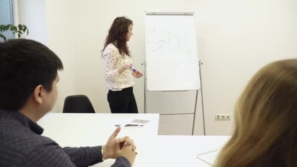 Mladá krásná žena je psaní na tabuli na konferenci — Stock video