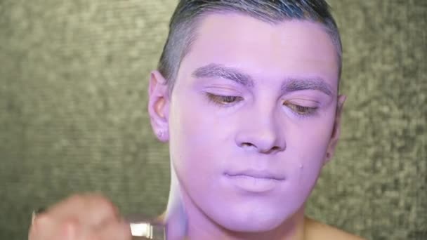 Καλλιτέχνης μακιγιάζ καλύπτει νέοι επανδρώνει το λαιμό με ένα closeup βιολετί χρώμα — Αρχείο Βίντεο
