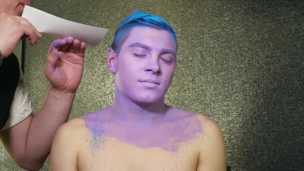 Maquiagem artista sopra brilhos azuis para o cabelo dos homens — Vídeo de Stock