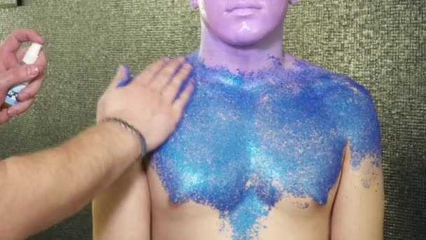 Body art specialist som täcker ungarna mans kropp med gnistrar — Stockvideo