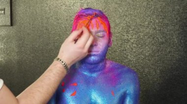 Yüz makyaj sanatçı yayılır turuncu boya genç üzerinde mans