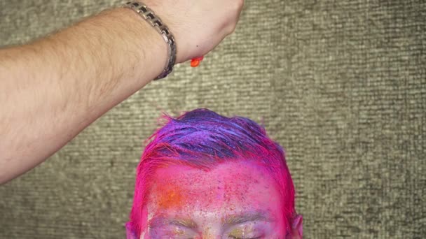 Виробник мистецтва тіла наливає помаранчеву фарбу на волосся чоловіка — стокове відео