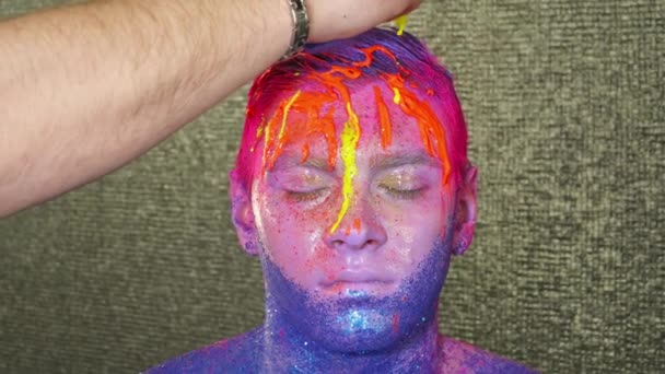Виробник мистецтва тіла наливає жовту фарбу на обличчя чоловіка — стокове відео