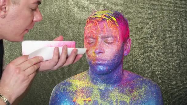 Maquillaje artista soplando destellos amarillos a la cara de los hombres — Vídeos de Stock