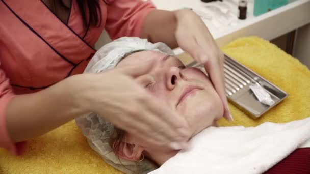 Beautician covering womans face with gel after the anti aging procedure in salon closeup — Stock Video