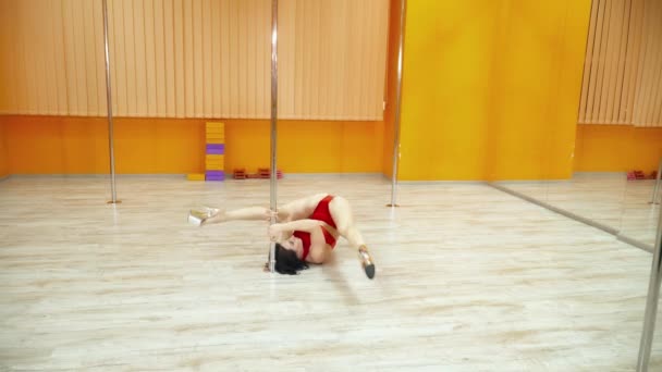 Attractive young woman dancing exotic dance near the pole in the studio — Stock Video