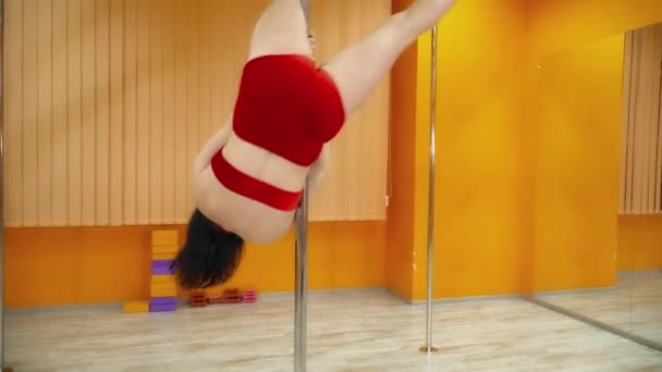 Brunette woman dancing exotic dance near the pole in the pole dance studio — Stock Video