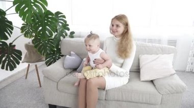 Onun bebek çocuk ile kanepede oturan genç mutlu anne