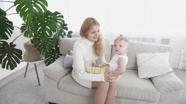 Ung glad mamma som sitter i soffan med sin lilla baby pojke — Stockvideo