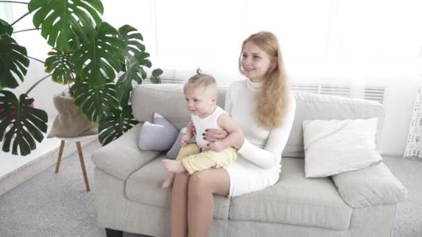 Junge glückliche Mutter sitzt auf dem Sofa mit ihrem kleinen Jungen — Stockvideo