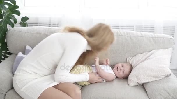 Jovem mãe brincando com seu pequeno filho no sofá — Vídeo de Stock