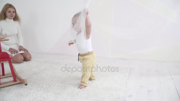 Смішний маленький хлопчик грає з білими шторами — стокове відео