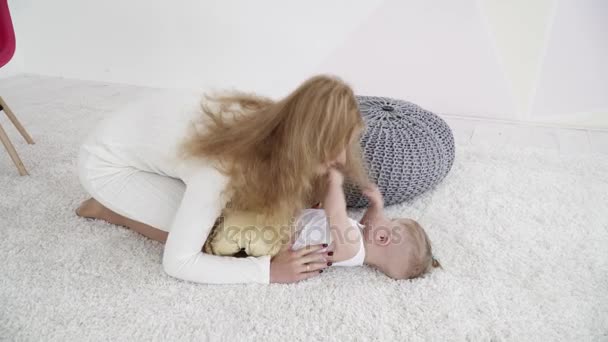 Мама играла со своим маленьким мальчиком, лежащим на ковре — стоковое видео