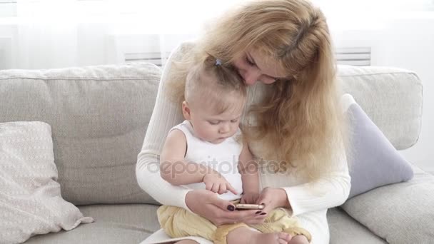 Ung söt mamma visar något på smartphone hennes lilla barn — Stockvideo