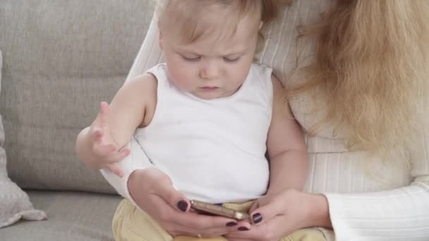 Bir şey onun erkek bebek smartphone üzerinde gösterilen genç güzel anne — Stok video