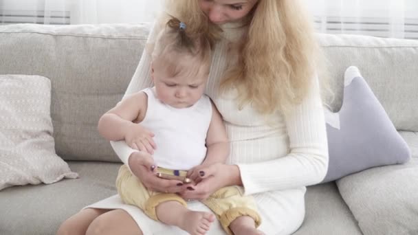 Joven bonita madre mostrando algo en el teléfono inteligente su pequeño niño — Vídeos de Stock