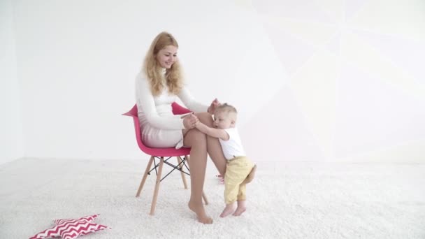 Pequeño bebé niño está montando en su madre pierna — Vídeos de Stock