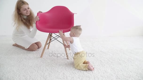 Молодая мать играет в прятки со своим маленьким мальчиком в комнате — стоковое видео
