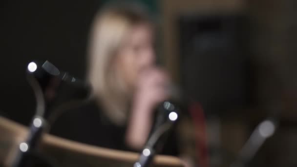 Крупный план гитары с женщиной, поющей под микрофон на заднем плане — стоковое видео