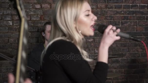 Молодая женщина поет на репетиции рок-группы — стоковое видео