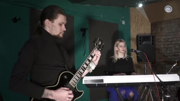 Beautiful woman singing and playing the synthesiser and man playing the guitar — Stock Video