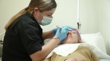 Güzellik uzmanı bir kadın için bir kaş kalıcı makyaj yapıyor