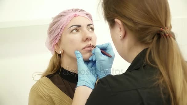 Esteticista preparando a la joven para el maquillaje permanente — Vídeo de stock