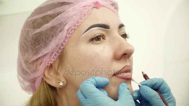 Esteticista preparando a la joven para el maquillaje permanente de los labios — Vídeo de stock