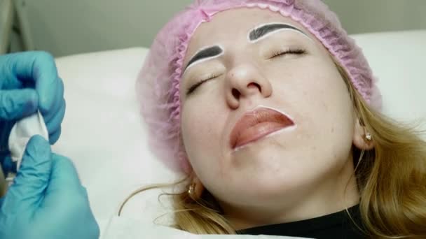 Beautician is clearing lips during the permanent makeup procedure — Stock Video