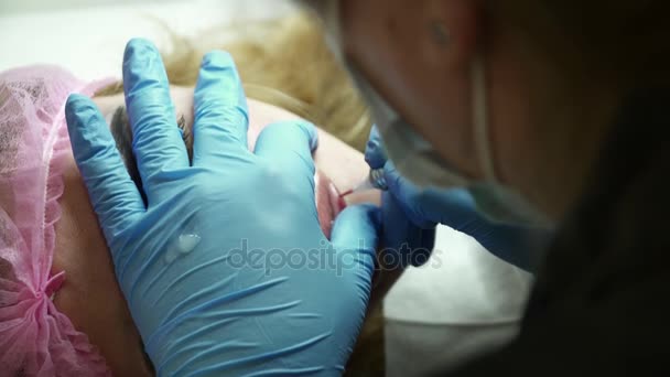 Cosmetologist fazendo a maquiagem permanente para uma jovem mulher close-up — Vídeo de Stock