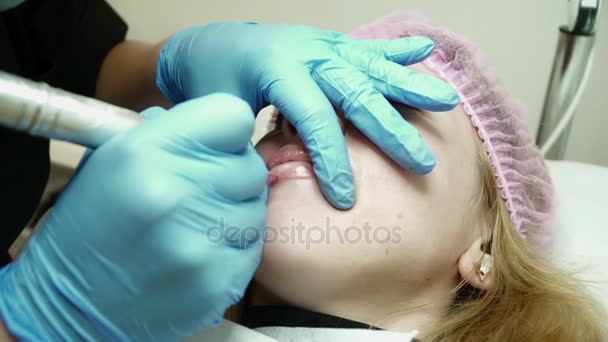 Cosmetologist está preenchendo os lábios das mulheres jovens com maquiagem permanente — Vídeo de Stock
