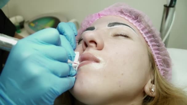 Cosmetologist is clearing womans lips after the permanent makeup — Stock Video