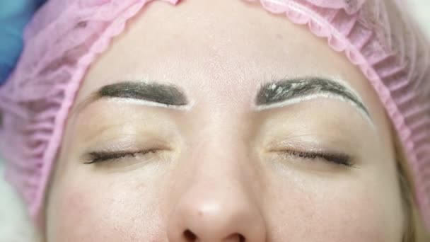 Cosmetologist is making an eyebrow permanent makeup in salon closeup — Stock Video