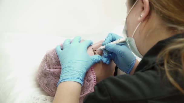 Косметик делает брови постоянным макияжем в салоне — стоковое видео