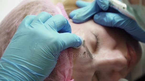 Esteticista está haciendo una ceja permanente maquillaje para una mujer joven — Vídeos de Stock