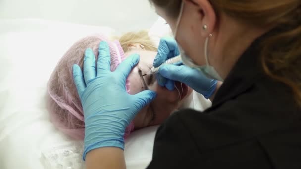 Schoonheidsspecialiste is het maken van een wenkbrauw permanente make-up voor een vrouw in de salon — Stockvideo