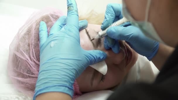 Closeup of beautician is making an eyebrow permanent makeup in salon — Stock Video