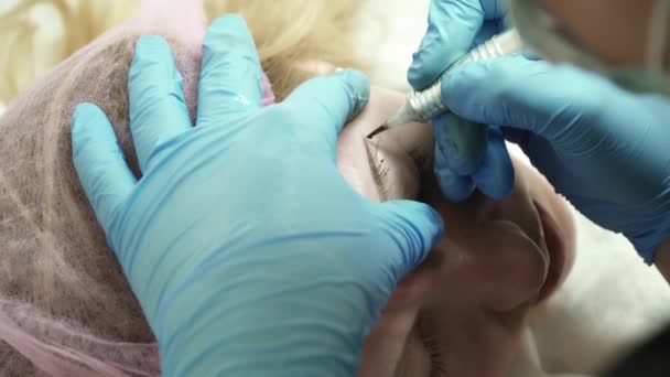Primer plano del cosmetólogo está haciendo una ceja maquillaje permanente para una mujer en el salón — Vídeos de Stock