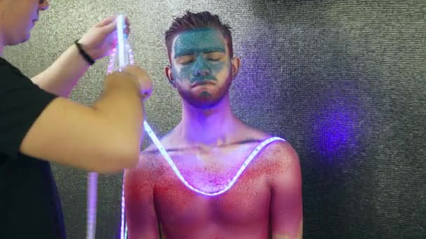 Truccatore pone le luci fata al giovane con body art — Video Stock